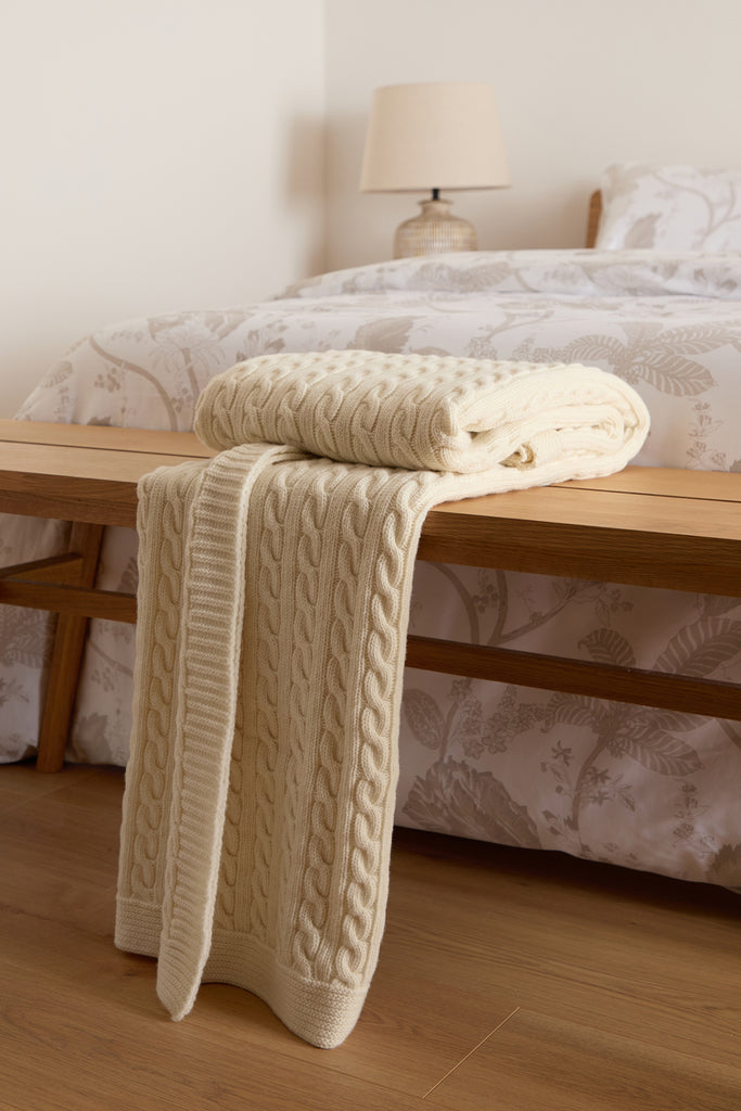 Foxford Cable Knit Cream Merino Bed Blanket (130x170 cm), designed in Ireland, featuring a classic cable knit pattern in soft merino wool.