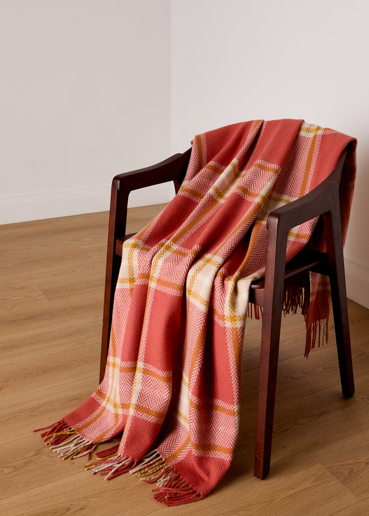 draped over a throw The Foxford Macha Lambswool and Cashmere Throw combines the finest craftsmanship with luxurious warmth. Woven in our County Mayo mill, this throw features a rich terracotta check design that adds a warm, inviting touch to any room. The blend of lambswool and cashmere ensures ultimate softness and comfort, making it perfect for cosy evenings or as a stylish accent piece for your home. Embrace the elegance of Irish design with this timeless throw that will effortlessly complement any inter