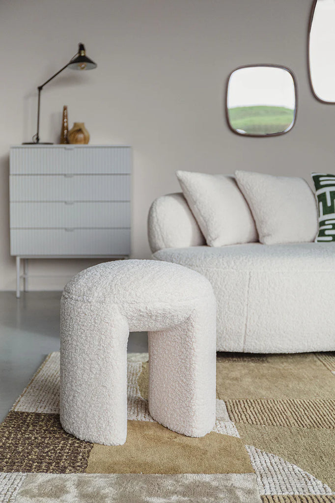 The Foxford Cloud Bouclé Stool offers a seamless combination of both comfort and style. Its trendy and chic design is sure to elevate any living space. With its crisp white bouclé upholstery, also known as teddy fabric, this stool exudes elegance. The foam seat ensures a comfortable sitting experience, making it the perfect spot to unwind and relax. Its organic contours and light appearance make it effortless to move as needed, providing an extra touch of convenience to any room.