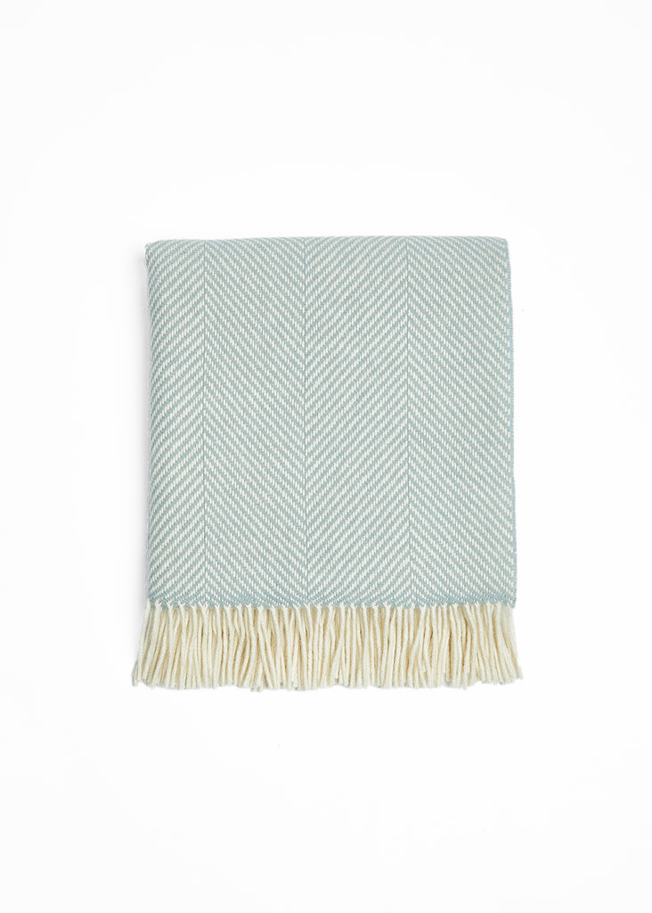 Transform your living space with the luxurious Foxford Aqua and White Merino Throw. Handcrafted from premium Merino wool at our County Mayo, Ireland mill, this stunning throw features a classic aqua and white giant herringbone pattern. Immerse yourself in the unmatched softness and warmth of Merino wool. Versatile and timeless, this throw will elevate the look and feel of any room.